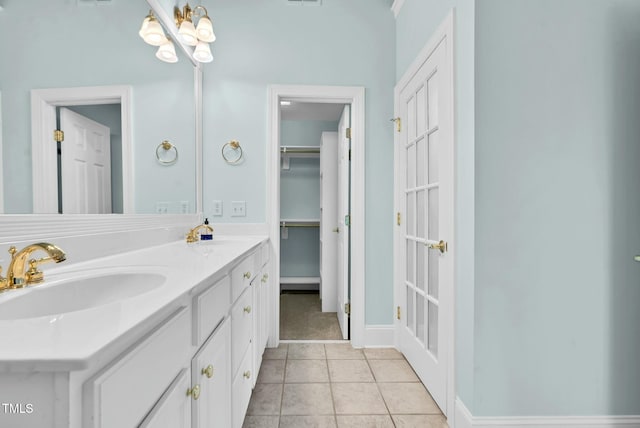 bathroom featuring tile patterned floors, baseboards, double vanity, and a sink