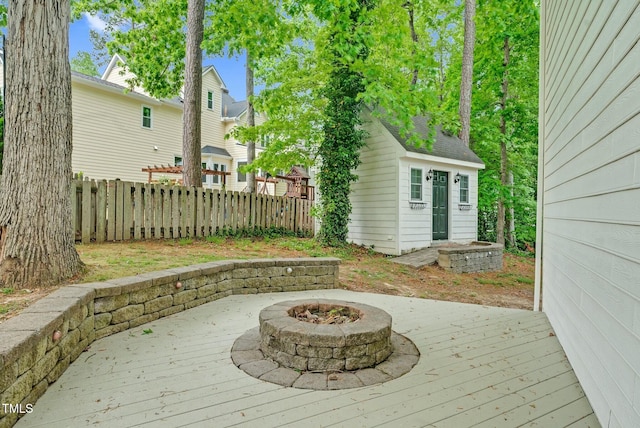 wooden deck with an outdoor fire pit, fence, and an outdoor structure