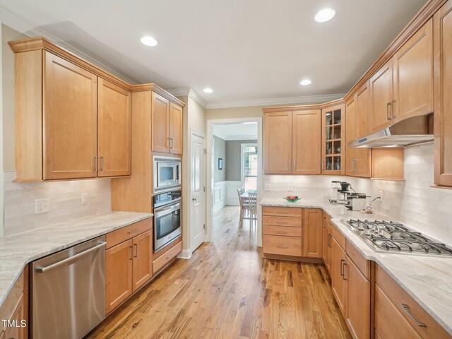4125 Enfield Ridge Dr, Cary, NC 27519 - kitchen featuring appliances with stainless steel finishes, under cabinet range hood, ornamental molding, glass insert cabinets, and light wood-style flooring