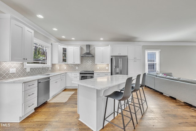 725 S State St, Raleigh, NC 27601 - kitchen featuring stainless steel appliances, a kitchen breakfast bar, a sink, wall chimney range hood, and crown molding