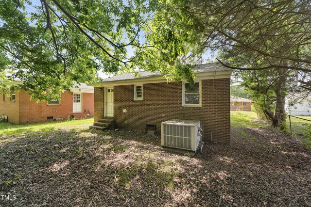 back of property featuring entry steps, crawl space, central AC, and brick siding