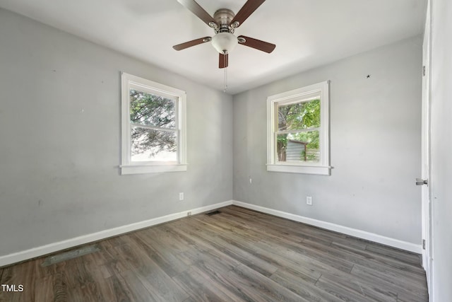 spare room with healthy amount of natural light, baseboards, and wood finished floors