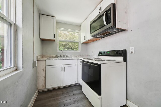 kitchen featuring range with electric cooktop, stainless steel microwave, a sink, and white cabinetry