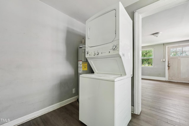 clothes washing area with stacked washer / drying machine, wood finished floors, and baseboards