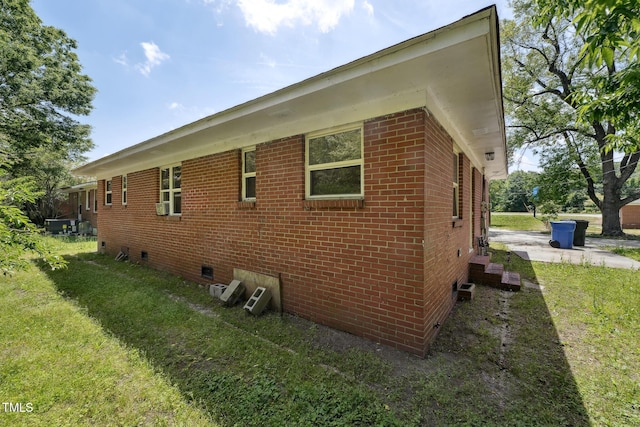 view of side of property featuring crawl space, brick siding, and a yard