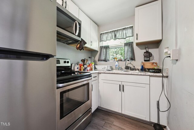 kitchen with stainless steel appliances, a sink, dark wood finished floors, and white cabinets