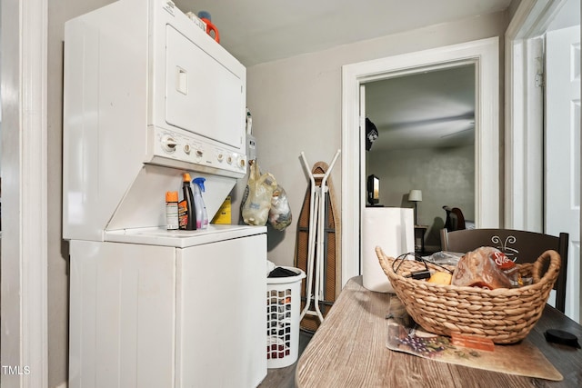 clothes washing area featuring stacked washer and clothes dryer and wood finished floors