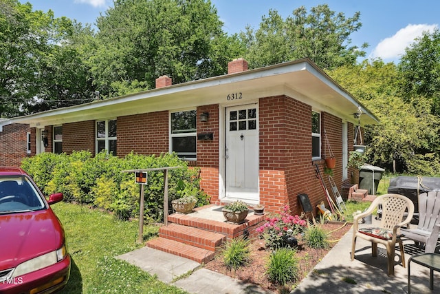 single story home with a chimney and brick siding