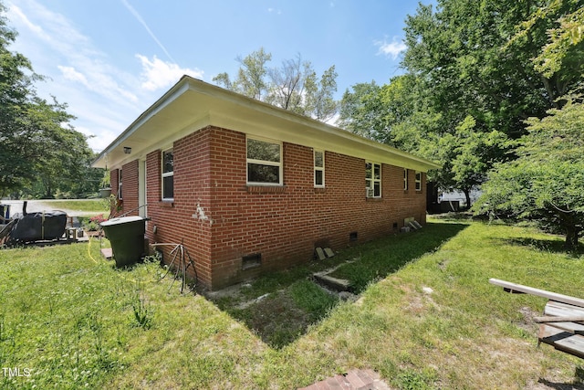 view of property exterior featuring crawl space, a yard, and brick siding
