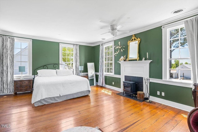 7348 NC-222 Hwy, Stantonsburg, NC 27883 - bedroom featuring a wood stove, visible vents, hardwood / wood-style floors, baseboards, and ornamental molding