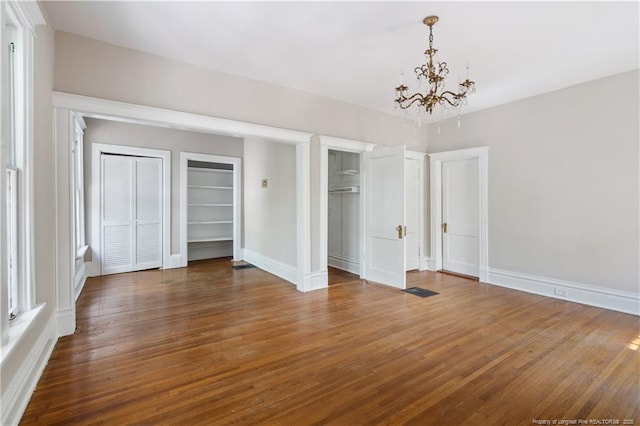 116 Hawthorne Rd, Raleigh, NC 27605 - unfurnished bedroom featuring baseboards, two closets, wood finished floors, and a chandelier