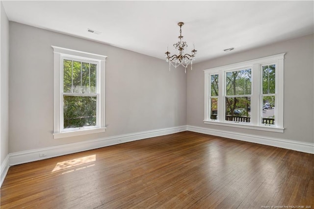 116 Hawthorne Rd, Raleigh, NC 27605 - unfurnished dining area with visible vents, baseboards, an inviting chandelier, and hardwood / wood-style flooring