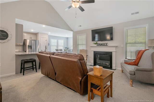 living area featuring a ceiling fan, a fireplace with flush hearth, light carpet, baseboards, and visible vents