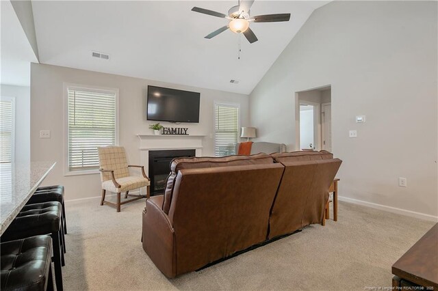 living area with visible vents, baseboards, a fireplace, light colored carpet, and ceiling fan
