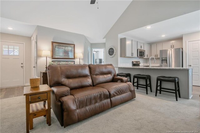 living area with recessed lighting, vaulted ceiling, and light colored carpet
