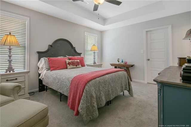 bedroom featuring a ceiling fan, baseboards, a raised ceiling, and light colored carpet