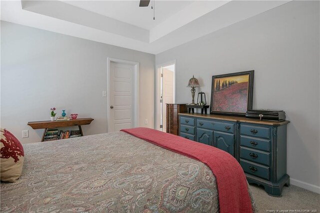 bedroom with light colored carpet, baseboards, a ceiling fan, and a raised ceiling