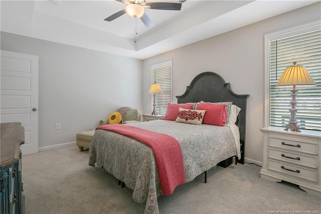 bedroom featuring a raised ceiling, baseboards, multiple windows, and carpet