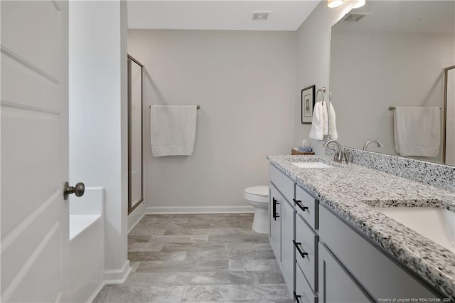 bathroom with a shower stall, toilet, a sink, baseboards, and visible vents
