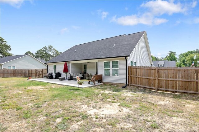 rear view of house featuring a shingled roof, a lawn, a fenced backyard, and a patio