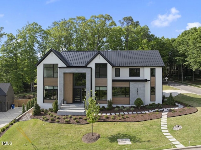 view of front facade featuring stucco siding, metal roof, and a front lawn