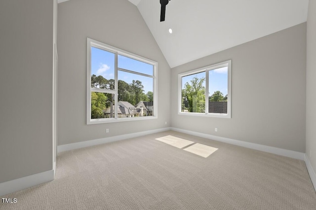 carpeted spare room with baseboards, vaulted ceiling, and plenty of natural light