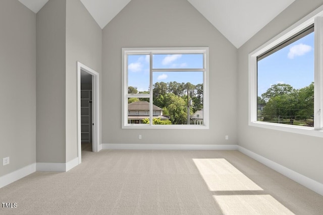 carpeted spare room with a wealth of natural light, vaulted ceiling, and baseboards