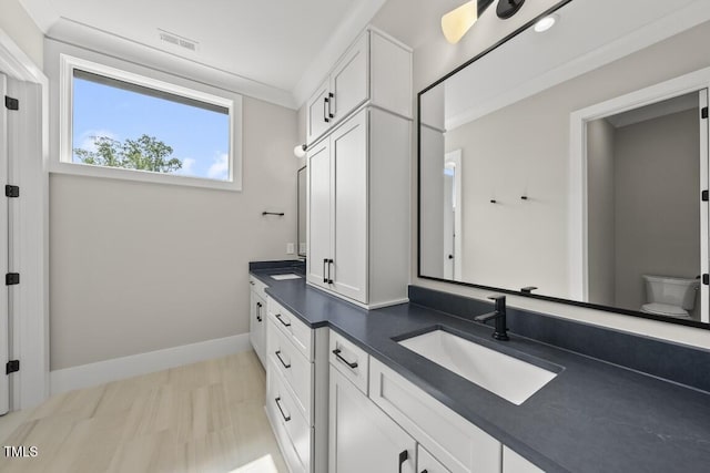 full bathroom with a sink, toilet, double vanity, visible vents, and baseboards