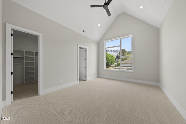 unfurnished bedroom with a walk in closet, baseboards, lofted ceiling, and carpet flooring