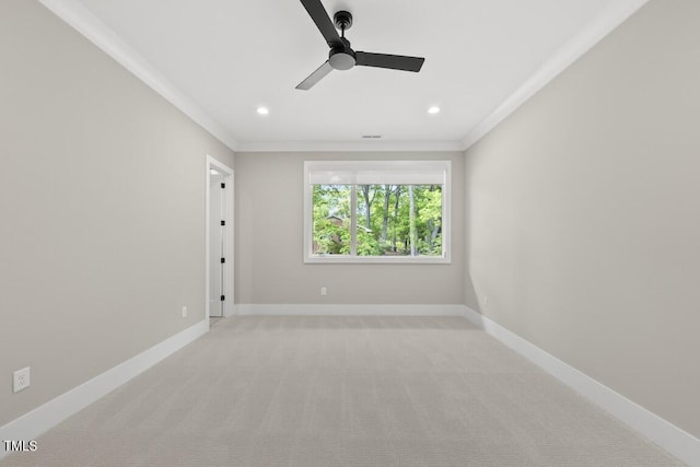 empty room featuring crown molding, a ceiling fan, light colored carpet, and baseboards