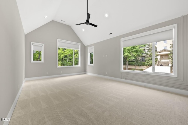 unfurnished room with a wealth of natural light, ceiling fan, vaulted ceiling, and light carpet