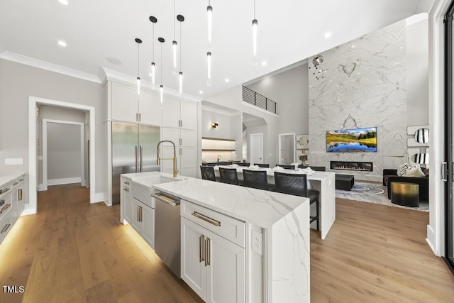 kitchen featuring stainless steel dishwasher, a spacious island, a fireplace, a sink, and open floor plan