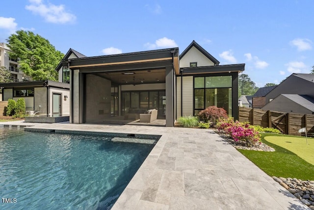 back of property featuring fence, an outdoor pool, a sunroom, and a patio area