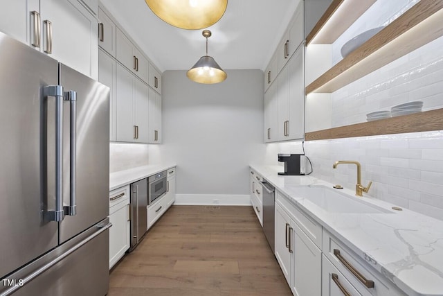 kitchen featuring stainless steel appliances, open shelves, backsplash, a sink, and baseboards