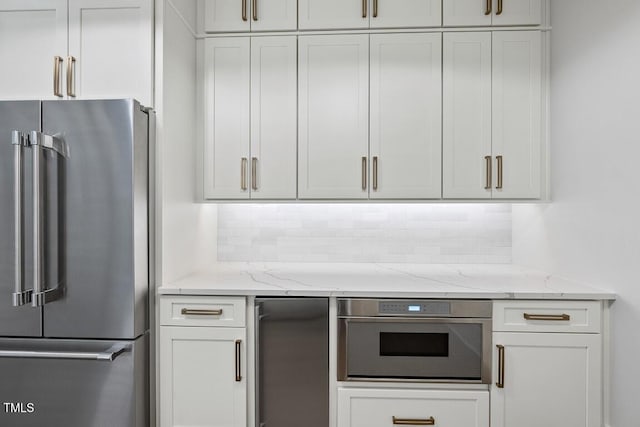 kitchen featuring light stone counters, white cabinets, backsplash, and stainless steel appliances