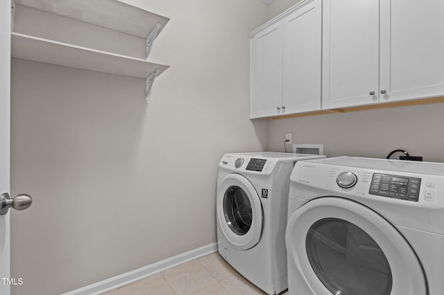 clothes washing area with separate washer and dryer, baseboards, cabinet space, and light tile patterned floors