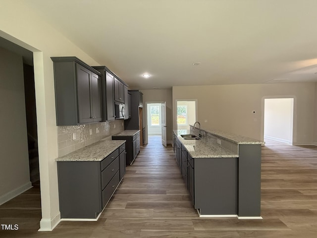 93 Hot Springs Way, Benson, NC 27504 - kitchen with decorative backsplash, light wood-type flooring, light stone countertops, and a kitchen island with sink
