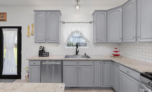 kitchen featuring stainless steel appliances, gray cabinetry, backsplash, and a sink