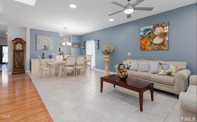 living room with recessed lighting, baseboards, and ceiling fan with notable chandelier