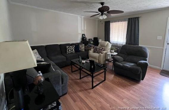 living room with ornamental molding, a ceiling fan, wood finished floors, and a textured ceiling