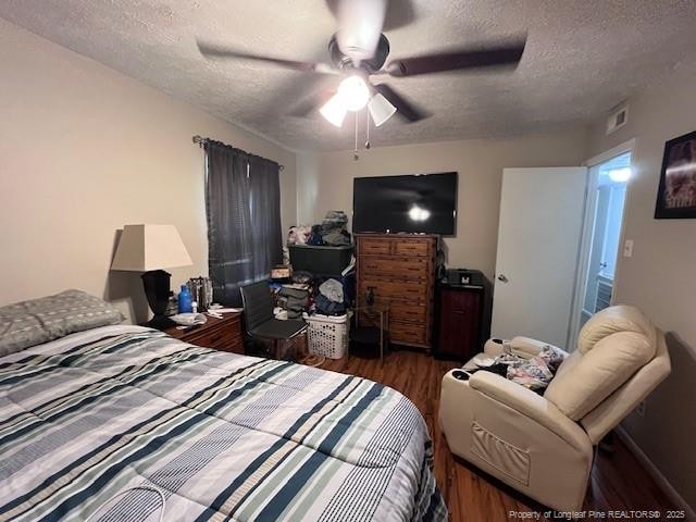 bedroom with a ceiling fan, wood finished floors, a textured ceiling, and visible vents