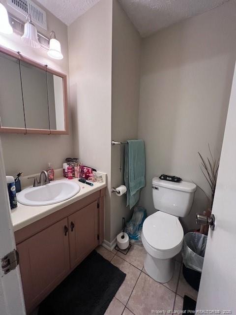 bathroom with tile patterned floors, a textured ceiling, vanity, toilet, and visible vents