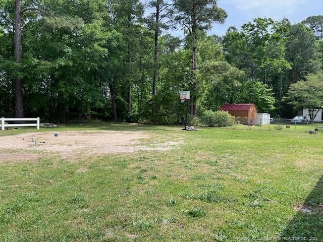 view of yard featuring a storage shed, fence, and an outdoor structure