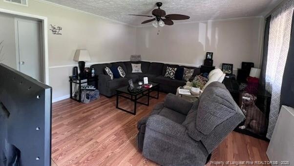 1725 Sand Hill Rd, Hope Mills, NC 28348 - living area featuring a ceiling fan, a textured ceiling, visible vents, crown molding, and wood finished floors
