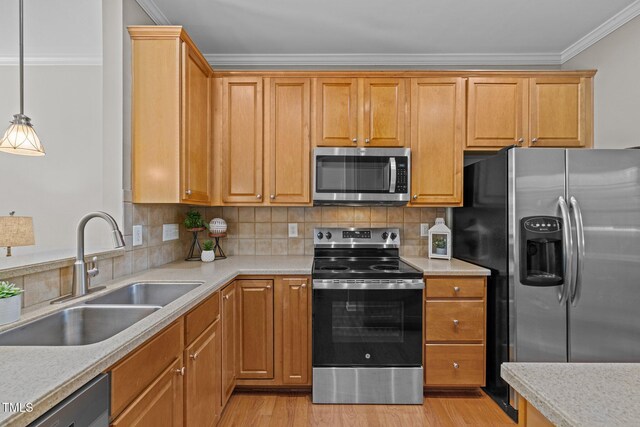 kitchen featuring stainless steel appliances, a sink, crown molding, light countertops, and light wood-style flooring