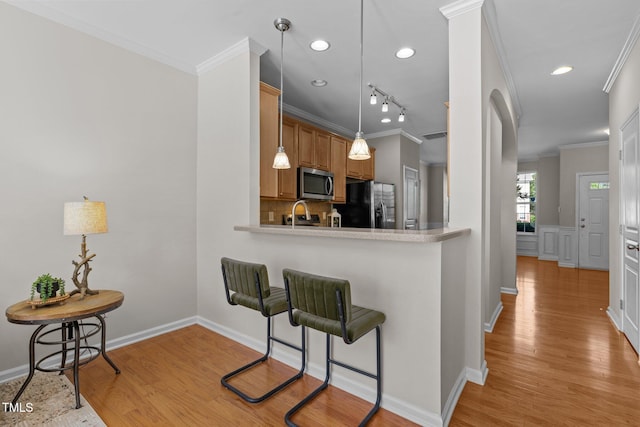 kitchen featuring stainless steel microwave, black fridge with ice dispenser, light wood finished floors, light countertops, and ornamental molding