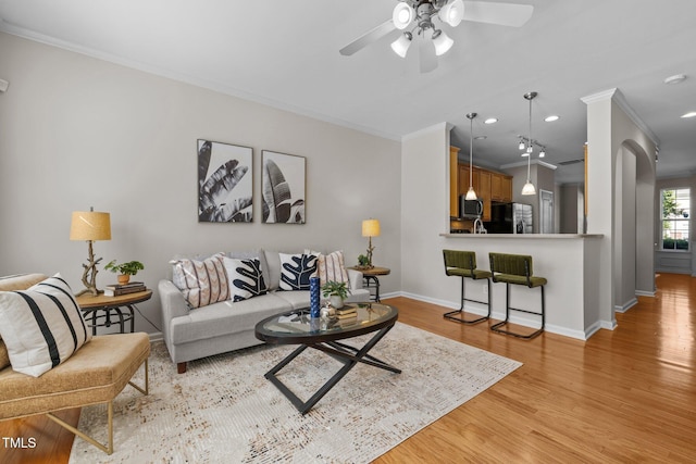 living area with crown molding, baseboards, ceiling fan, light wood-type flooring, and recessed lighting