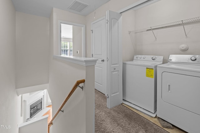 clothes washing area featuring washer and clothes dryer, light carpet, and attic access