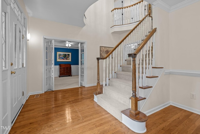 entryway with wood finished floors, baseboards, stairs, a ceiling fan, and crown molding