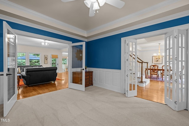 spare room with french doors, a chandelier, carpet floors, ornamental molding, and a wainscoted wall